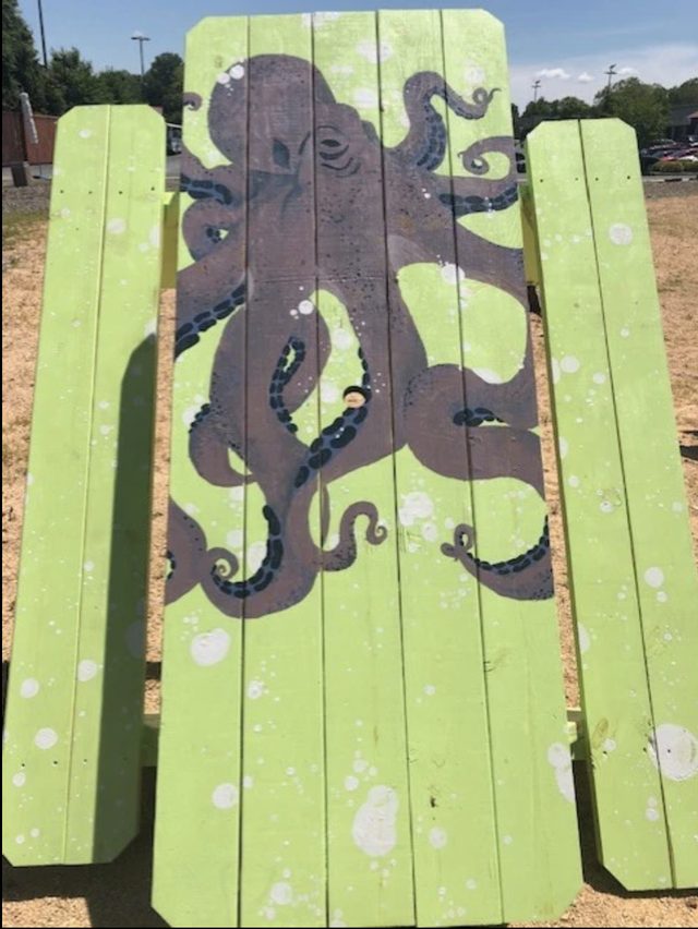 A lime green picnic table painted with a large purple octopus