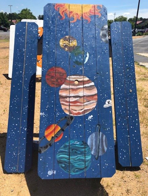 A navy picnic table painted with the sun and planets of the solar system